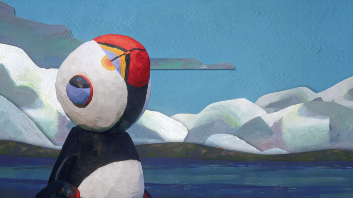 Animated film still: a penguin looks up at the sky, with the sea, shoreline, and mountains in the background beneath an almost entirely blue sky.